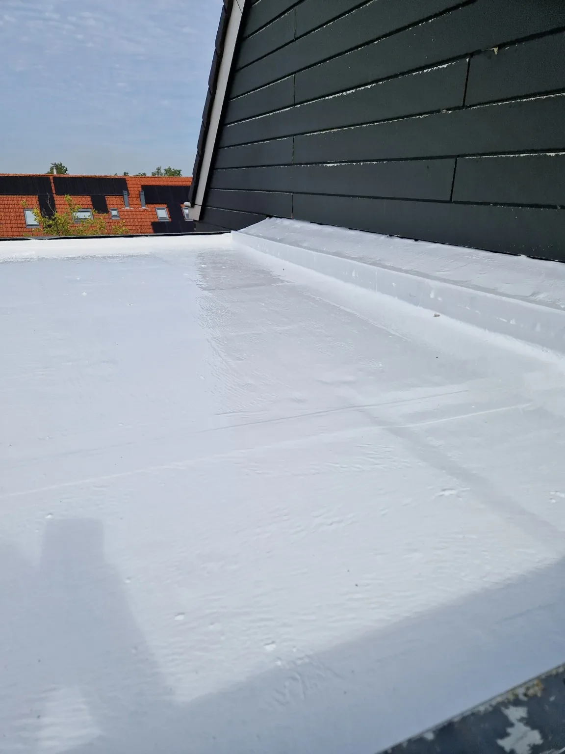 Afgewerkte gevelaansluiting bij bitumendak in hellevoetsluis met siliconen dakcoating